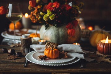 Elegant atmospheric beautiful dinner table setting for thanksgiving or wedding celebration, fall countryside style, pumpkins as decor. Romantic cozy home atmosphere. Wine, floral pumpkin centrepiece.