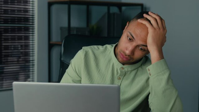 Desperate frustrated stressed african american man receive bad news by email on laptop in office evening sad worried shocked male businessman employee browsing computer crash error problem fail online