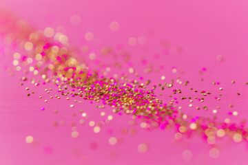 Golden pink sparkles on pink background. Light pink minimalistic festive glamorous background with scattered metal glitter in delicate pastel colors