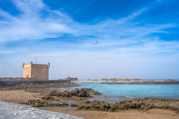 An ancient fortress stands beside the tranquil waters. Seagulls decorate the sandy beaches of...