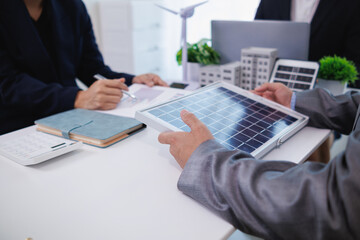 Businessmen, investors and electrical engineers discuss clean energy residential projects help...