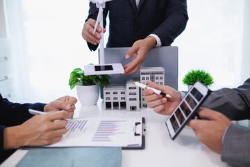 Businessmen, investors and electrical engineers discuss clean energy residential projects help...