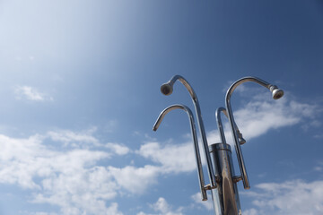 Beach Shower Heads Against Blue Sky. Group of metal shower heads standing high against a blue sky...
