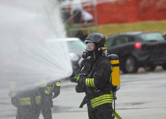 Firefighters with oxygen tanks spray a powerful stream of foam to extinguish the fire