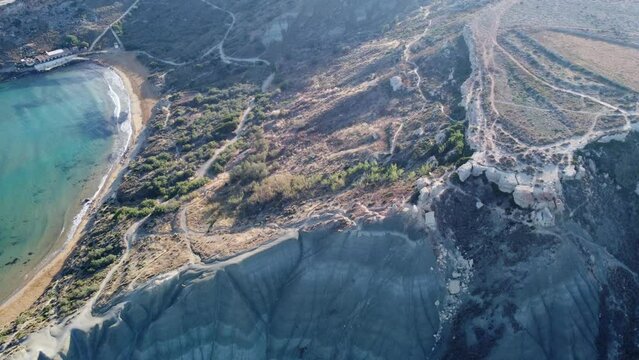 Aerial view of golden sand beach,. Ramla beach or Tuffieha beach from Il Qarraba rugged peninsula in the early morning. High quality 4k footage