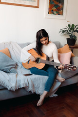 Young woman play guitar in the room