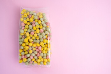 Sweet multi-colored flakes in packaging on a colored background. Fast food concept, space for text
