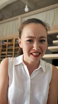 POV of young woman grimacing while discussing unpleasant subject with friend on video call. Dissatisfied lady feels bad looking in camera closeup Vertical Shot.
