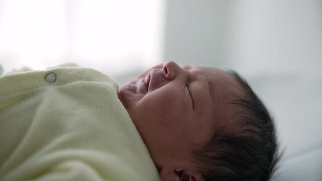 Newborn baby lying on a soft surface, dressed in a cozy cream outfit. calm and serene expression on the baby's face conveys a sense of tranquility and innocence,