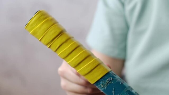 Close-up of the overgrip change on the racket. Woman Pulls the overgrip and wrapped it around the handle of racket.