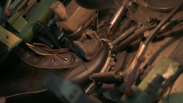 Industrial workers are using factory equipment to make shoes. Footwear production facility.