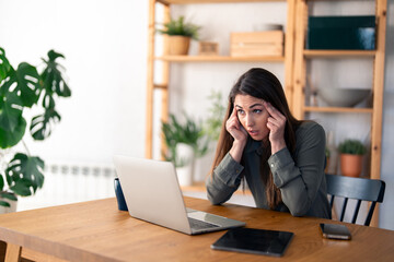 Young businesswoman sitting at desk in home office having tired look, having headache, being sleepy...