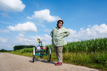 41 yo woman with the Down Syndrome standing next to her tricycle in the fields around Tienen,...