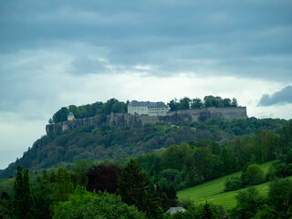 Fototapeta premium A hillside with a castle on top and a forest below. The sky is cloudy and the mood is peaceful