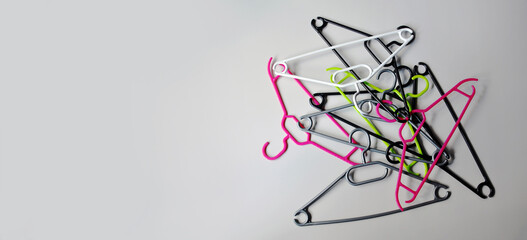 Stacked empty plastic clothes hangers on a light gray background. Minimalism. The concept of modern...