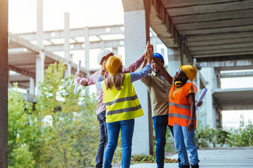 A team of construction professionals, dressed in safety gear, enjoy a moment of team spirit with a...