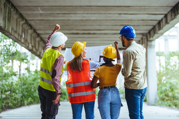 A diverse group of construction workers, adorned in safety helmets and reflective vests, actively...
