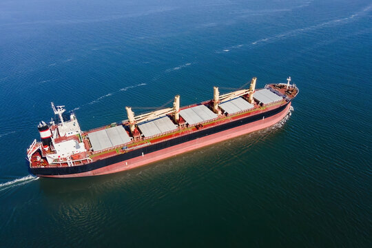 Aerial of cargo ship carrying for export dry bulk cargo from cargo yard port to other ocean, concept freight shipping ship on blue sea
