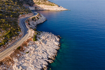 Aerial drone shot of a rocky coastline and coastal road near the sea with cars