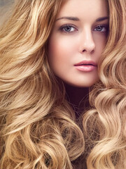 Obraz premium Beautiful modern blonde woman with volume hairstyle, long luxurious hair and beauty makeup, glamorous look face portrait for luxury fashion and natural cosmetics idea