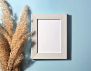 Mockup with blank photo frame and dried pampas grass over pastel blue background	