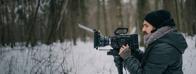 Fototapeta premium Director of photography with a camera in his hands on the set. Professional videographer at work on filming a movie, commercial or TV series