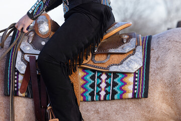 Western Show Saddle with rider wearing chaps close up