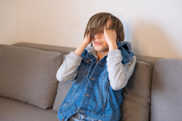 sad boy sits on couch covering face, abuse and deep emotional distress, Mental health crisis,...