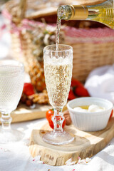 Picnic with wine, cheeses and fruits in the spring garden on a light tablecloth on a sunny day, almond blossoms. Shavuot, brunch.