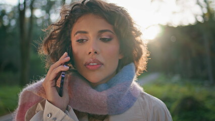 Serious woman ending call on phone at sunlit forest closeup. Lady talking nature