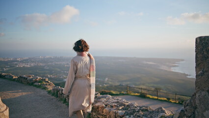 Explorer standing high viewpoint overlooking distant coastline cityscape. 