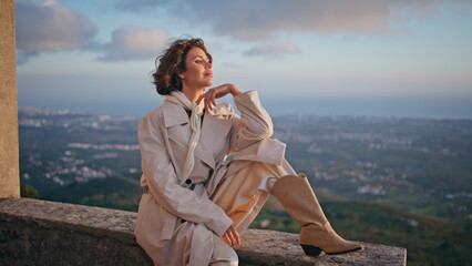 Lady posing cityscape backdrop at windy evening. Stylish woman traveler weekend