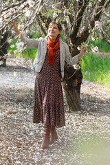A woman walks in the spring garden among blossoming almond trees