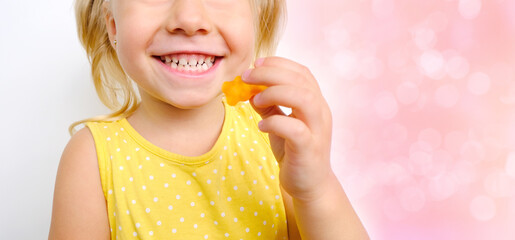 cheerful small child holds sweets, blonde girl 3 years old wants eat gelatinous candy with smile,...