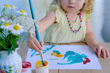 children's hand paints with brush, small child, little girl preschooler 3 years creates bright...