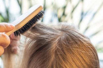 wooden comb, brush in female hand, woman, loving mother brushes, combing daughter's hair, young...