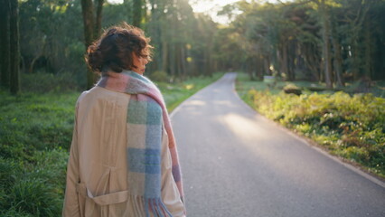 Stylish traveler walking forest path at sunlight. Lady wanderer enjoy journey 