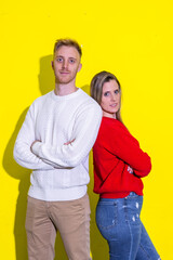 A man and a woman are standing next to each other on a yellow background