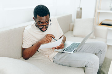 African American Man Freelancer Working and Smiling on Laptop in Modern Home Office