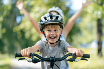Naklejka premium A boy wearing a helmet learning to ride a bicycle in a park