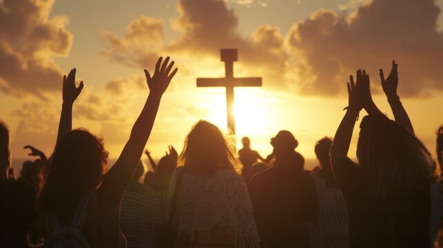 Christian worshipers raising hands up in the air in front of the cross.