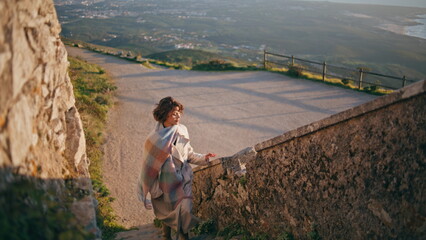 Adventurous woman climbing stairs of cultural landmark at soft evening sunlight.
