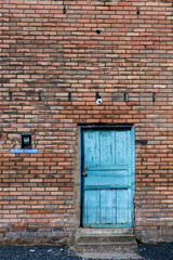 The old blue wooden door in a brick wall of a building in the town of Arcabuco, in the eastern Andean mountains of central Colombia.