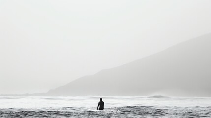 Foggy Ocean  A surfer sits on his board in the middle of a foggy ocean. The waves are small and the water is calm. - Powered by Adobe