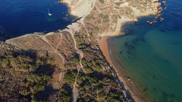 Qarraba Bay flat rock cape Malta, Aeriale stablishing shot in the morning sunlight showing hiking trekking path and two beaches on both side. High quality 4k footage