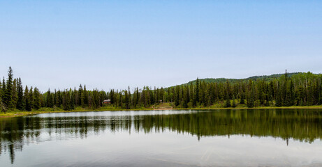 Reflections on lake that is surrounded by mountains and spruce trees.