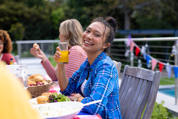 Portrait of happy diverse group of friends talking and having dinner at balcony with flags of usa