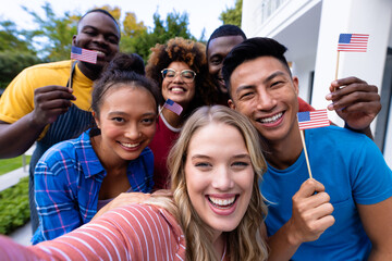 Portrait of happy diverse group of friends taking selfie and holding flags of usa