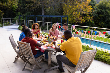 Happy diverse group of friends talking and having dinner with flags of usa