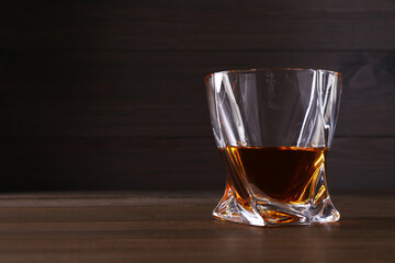 Delicious liqueur in glass on wooden table. Space for text